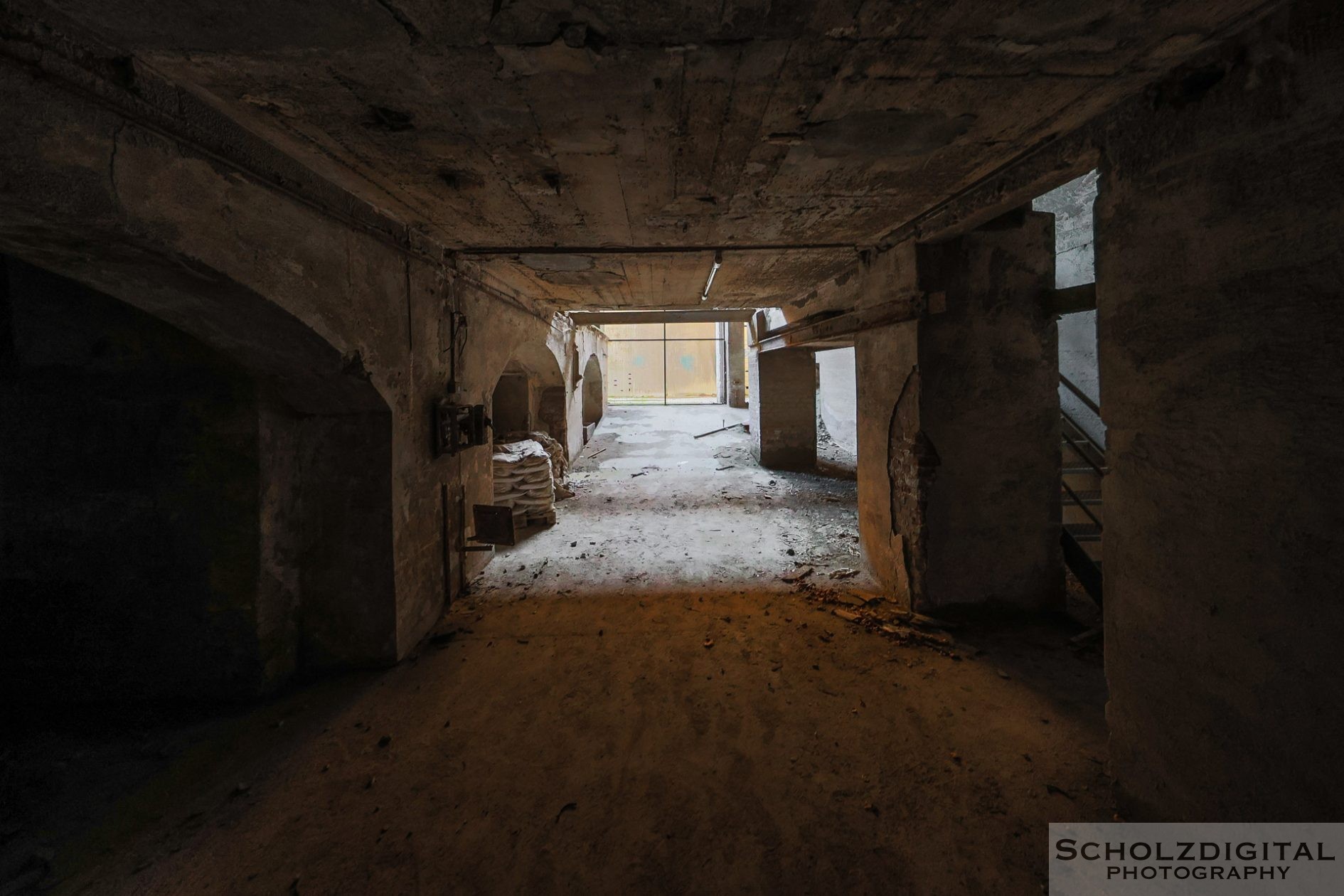Sonnenlicht fällt durch zerbrochene Fenster auf den staubigen Betonboden der verlassenen Fabrikhalle