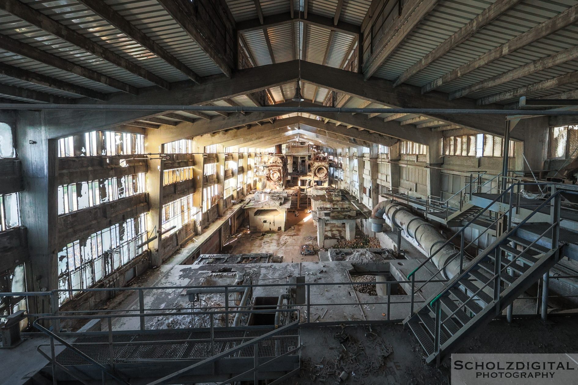 Sonnenlicht fällt durch zerbrochene Fenster auf den staubigen Betonboden der verlassenen Fabrikhalle