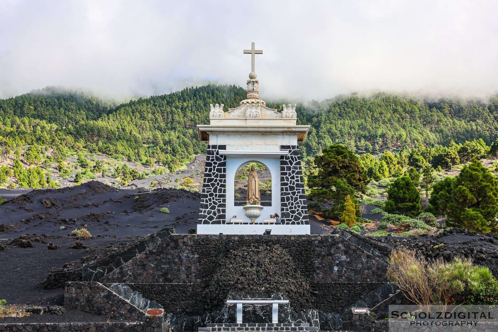 Denkmal am Vulkanhang mit Blick auf den von Lava betroffenen Ort